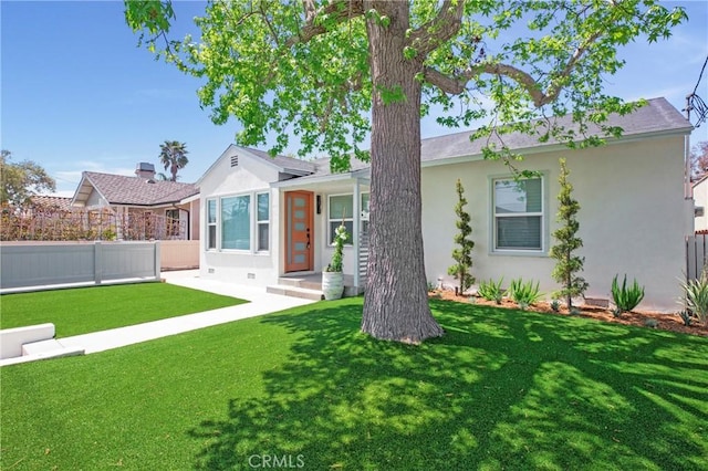 view of front of home with fence, a front lawn, and stucco siding