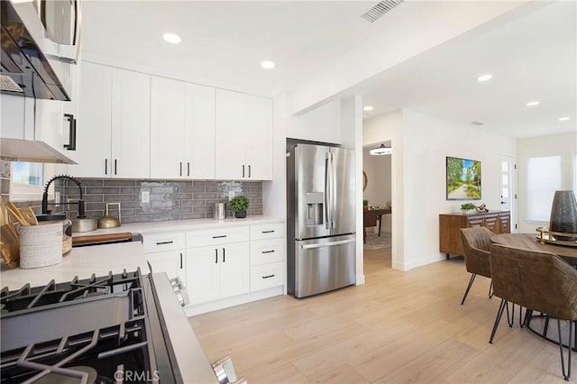 kitchen with recessed lighting, light countertops, light wood finished floors, backsplash, and stainless steel appliances
