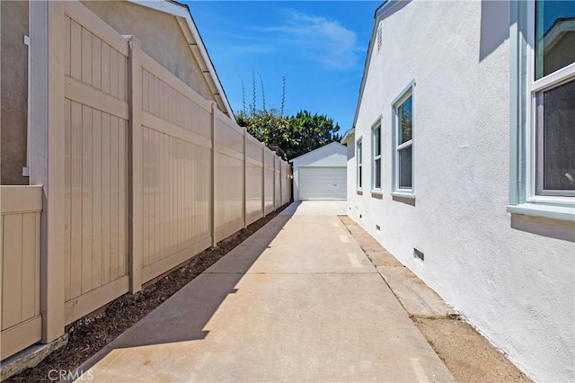 view of property exterior with a detached garage, fence, stucco siding, and crawl space