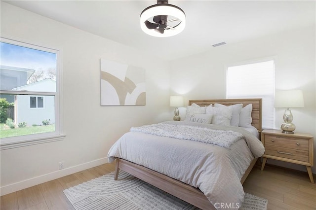 bedroom with baseboards, wood finished floors, and visible vents