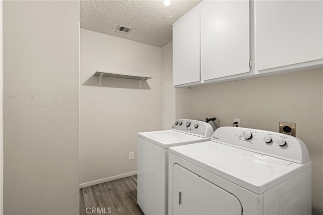 laundry area featuring visible vents, wood finished floors, baseboards, washer and clothes dryer, and cabinet space