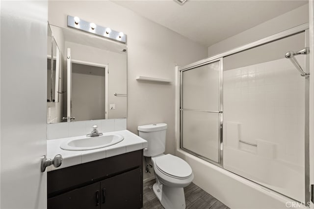 bathroom with toilet, enclosed tub / shower combo, wood finished floors, and vanity