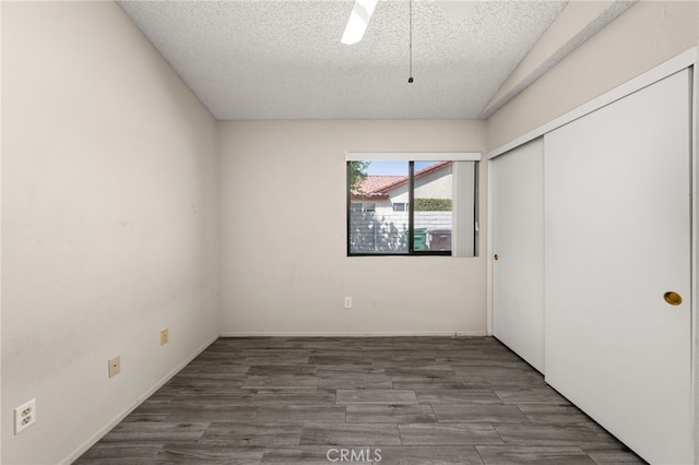 unfurnished bedroom with ceiling fan, a closet, a textured ceiling, and wood finished floors