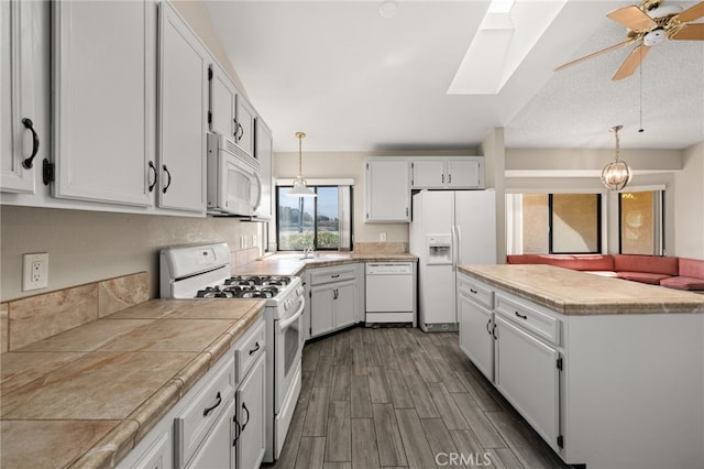kitchen featuring white appliances, a ceiling fan, decorative light fixtures, a skylight, and dark wood-style floors