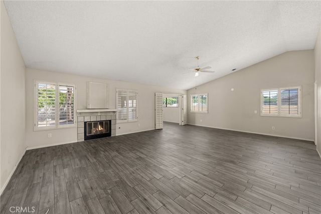 unfurnished living room featuring a ceiling fan, a wealth of natural light, and dark wood-style floors