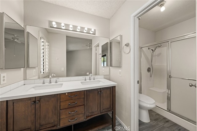 bathroom featuring a sink, ceiling fan, a stall shower, and toilet