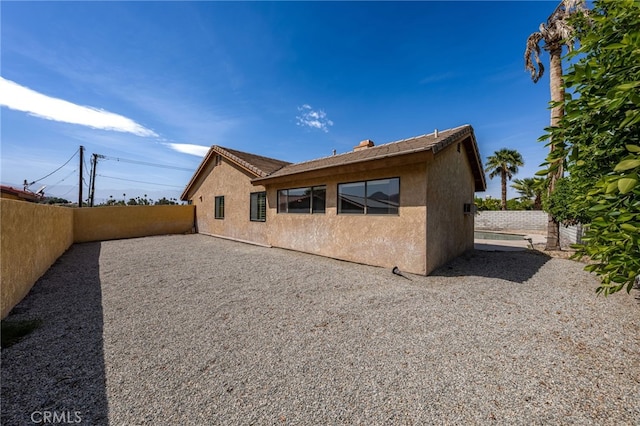 rear view of property with a fenced backyard and stucco siding