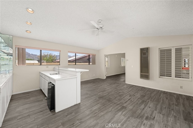 kitchen with ceiling fan, dark wood-style flooring, a sink, a peninsula, and a heating unit
