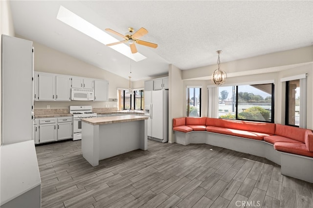 43922 Warner Trl, Palm Desert, CA 92211 - kitchen with white appliances, light countertops, vaulted ceiling, open floor plan, and white cabinetry