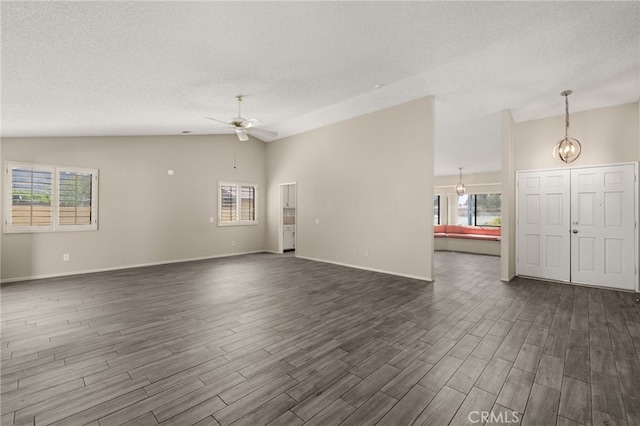 43922 Warner Trl, Palm Desert, CA 92211 - unfurnished living room featuring lofted ceiling, ceiling fan, dark wood-style floors, healthy amount of natural light, and a textured ceiling