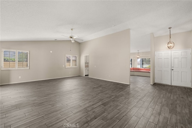 43922 Warner Trl, Palm Desert, CA 92211 - unfurnished living room featuring lofted ceiling, a textured ceiling, ceiling fan, dark wood finished floors, and plenty of natural light
