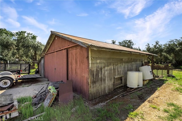 view of side of property with fence and an outbuilding