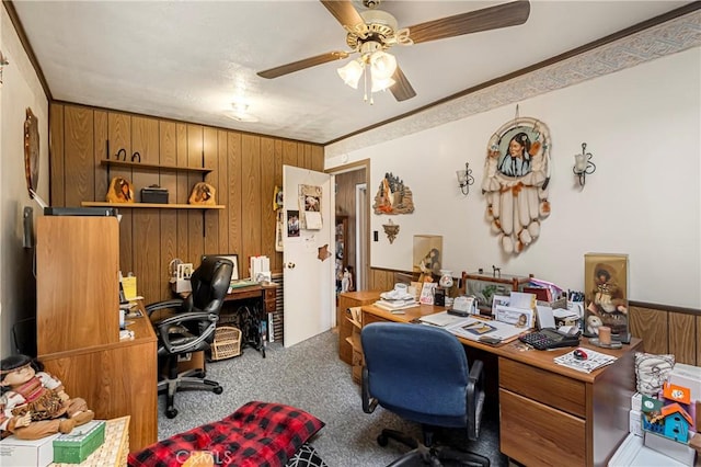 office area with wood walls, carpet, a ceiling fan, and a wainscoted wall