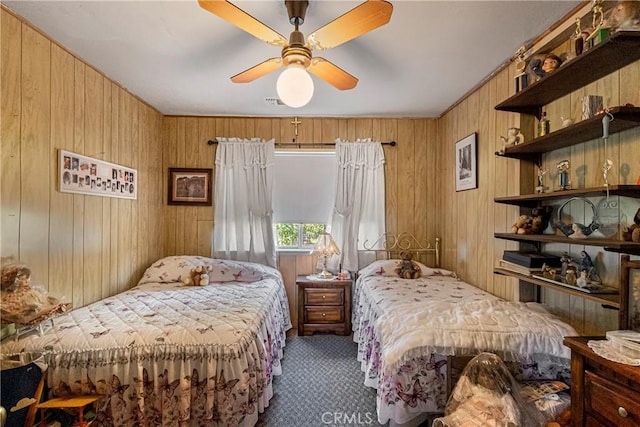 bedroom with wooden walls, a ceiling fan, and carpet flooring