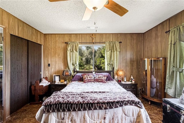 bedroom with wooden walls, a ceiling fan, a textured ceiling, and a closet