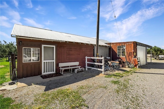back of property with an outdoor structure, fence, and metal roof