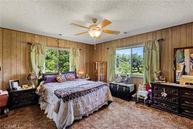 bedroom with visible vents, carpet floors, wooden walls, and multiple windows