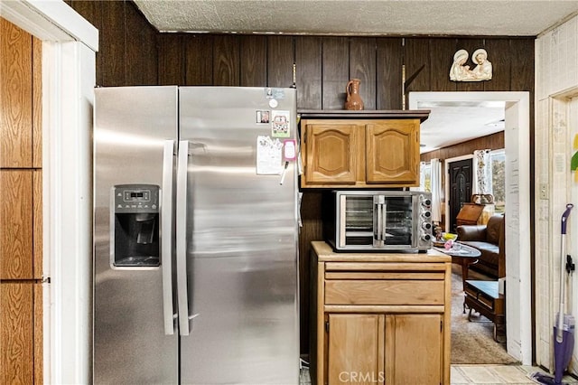 kitchen featuring a toaster, stainless steel fridge with ice dispenser, wooden walls, and light countertops