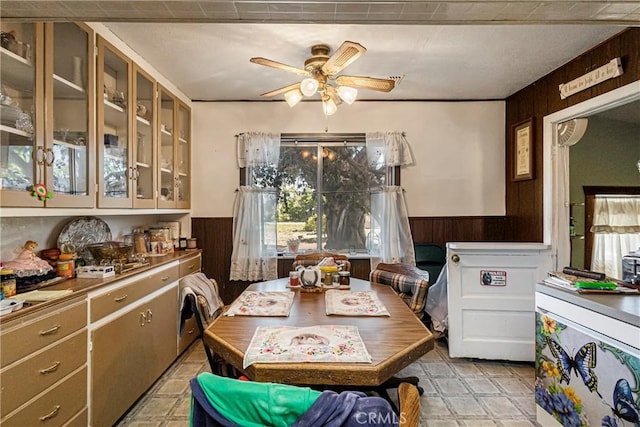 dining room featuring a ceiling fan, wainscoting, and wood walls