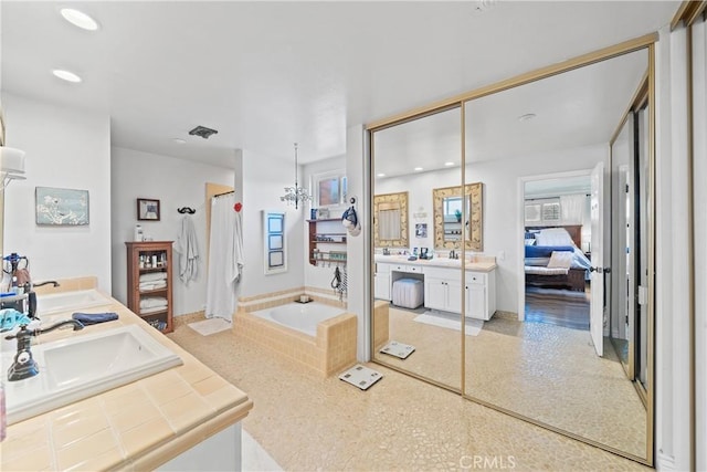 ensuite bathroom featuring connected bathroom, a walk in shower, a sink, double vanity, and a bath