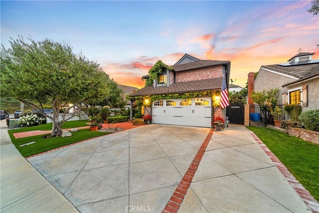 traditional-style house featuring a yard, fence, driveway, and brick siding