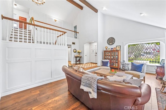 living area with arched walkways, beam ceiling, stairway, high vaulted ceiling, and wood-type flooring