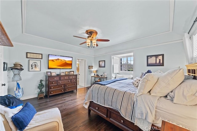 bedroom featuring baseboards, ceiling fan, wood finished floors, and a tray ceiling