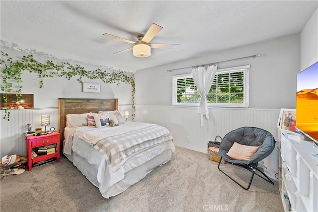 bedroom featuring carpet flooring, ceiling fan, and wainscoting