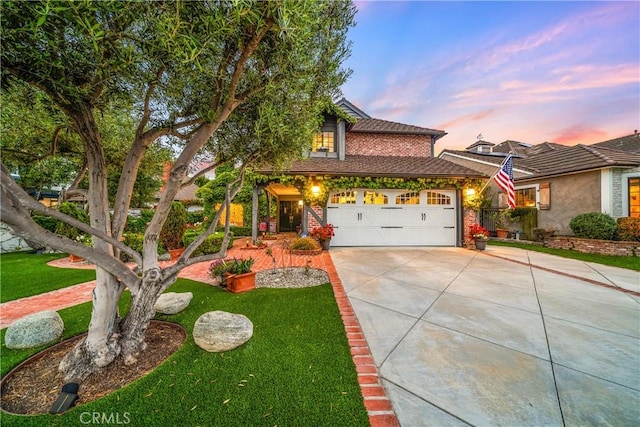 traditional home with an attached garage, a yard, driveway, and brick siding