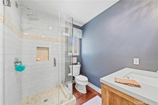 bathroom featuring vanity, wood finished floors, toilet, baseboards, and a shower stall