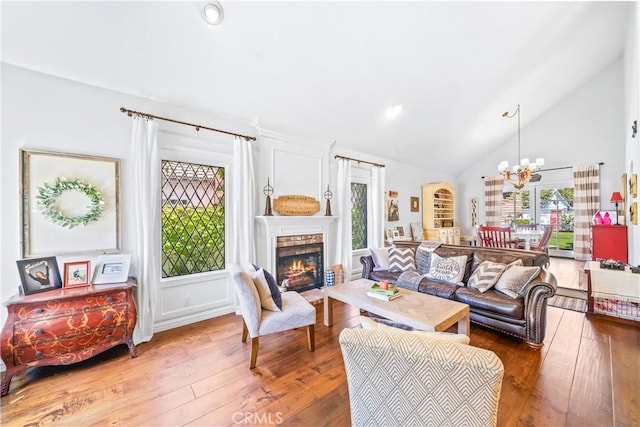 living room featuring a fireplace, high vaulted ceiling, an inviting chandelier, recessed lighting, and hardwood / wood-style floors