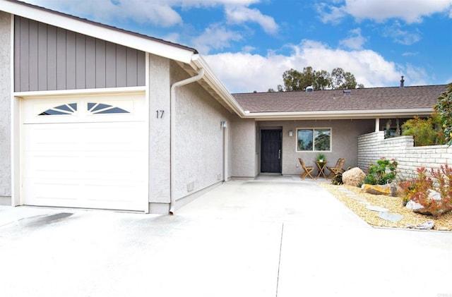 exterior space featuring a garage, stucco siding, and driveway
