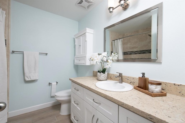 bathroom with visible vents, wood finished floors, baseboards, vanity, and toilet