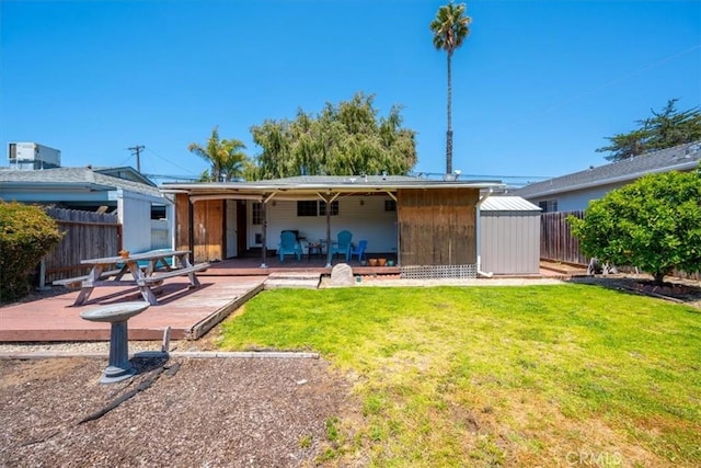 rear view of house with a yard, a wooden deck, and a fenced backyard