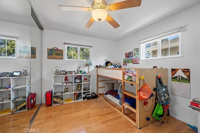 bedroom featuring a ceiling fan, wood finished floors, and multiple windows