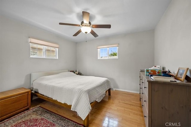 bedroom with baseboards, light wood finished floors, ceiling fan, and multiple windows
