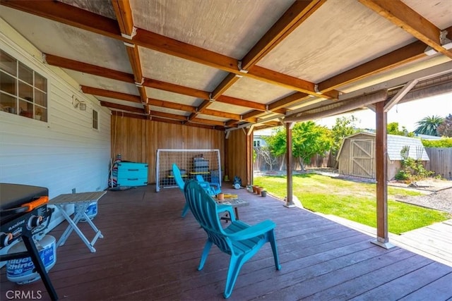 wooden terrace with a storage unit, a fenced backyard, a yard, and an outdoor structure