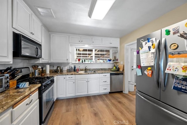 kitchen with visible vents, light wood-style floors, white cabinets, a sink, and appliances with stainless steel finishes