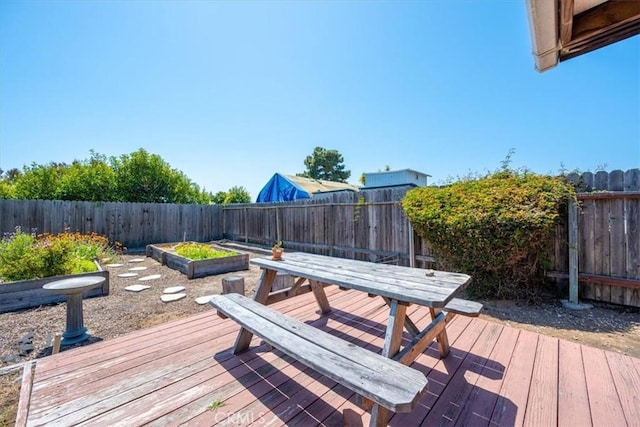 deck with a fenced backyard, outdoor dining space, and a vegetable garden