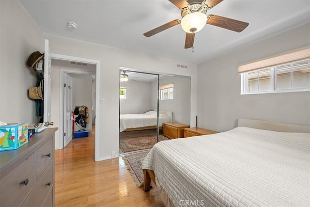 bedroom featuring light wood-type flooring, a ceiling fan, visible vents, and a closet