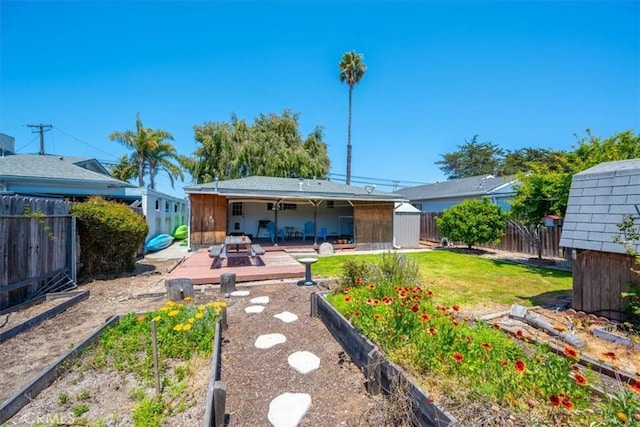 rear view of house featuring a fenced backyard, a wooden deck, a yard, and a garden