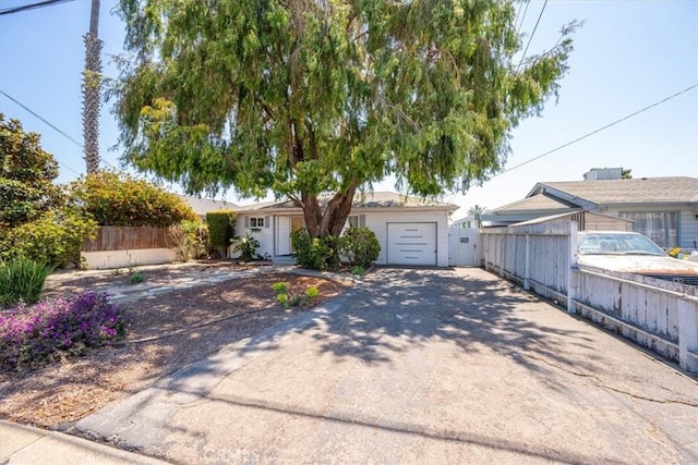 view of front of property featuring an attached garage, fence, and concrete driveway