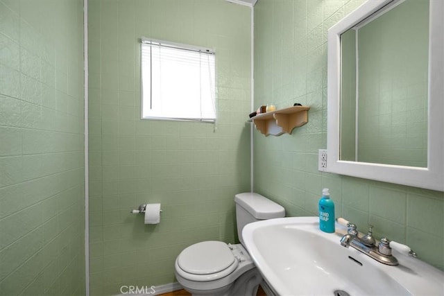 half bath featuring a sink, tile walls, and toilet