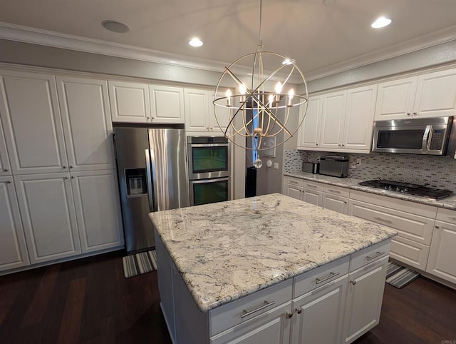 kitchen featuring appliances with stainless steel finishes, crown molding, a chandelier, a center island, and white cabinetry
