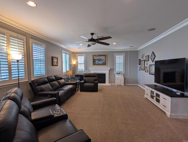 living area with a ceiling fan, carpet, a fireplace with raised hearth, crown molding, and baseboards