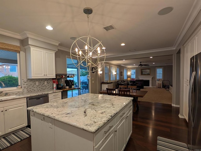 kitchen with crown molding, a sink, a kitchen island, white cabinets, and freestanding refrigerator