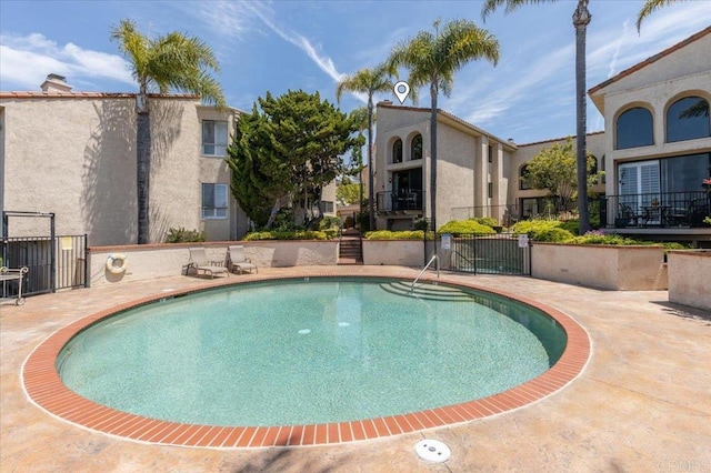 community pool with fence and a patio