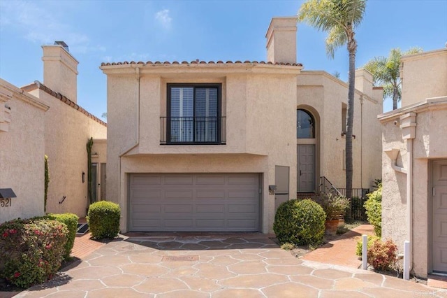 view of front facade with an attached garage, stucco siding, a chimney, and concrete driveway
