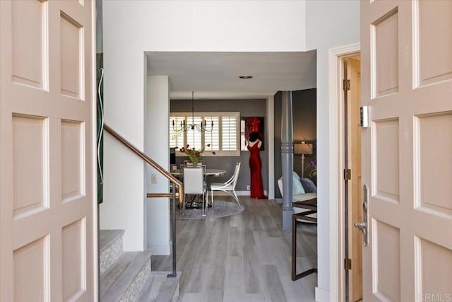 foyer with baseboards, stairs, wood finished floors, and a chandelier