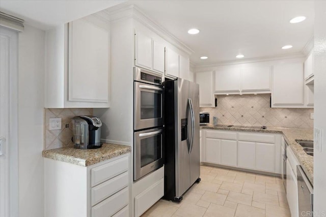 kitchen featuring light stone counters, stainless steel appliances, recessed lighting, white cabinetry, and decorative backsplash